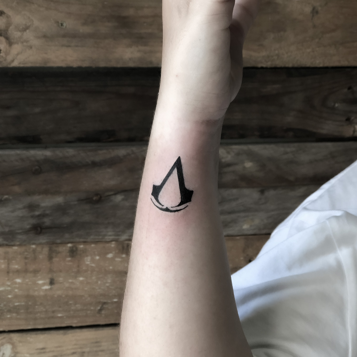 tatuaje blanco y negro símbolo Assassin's Creed
