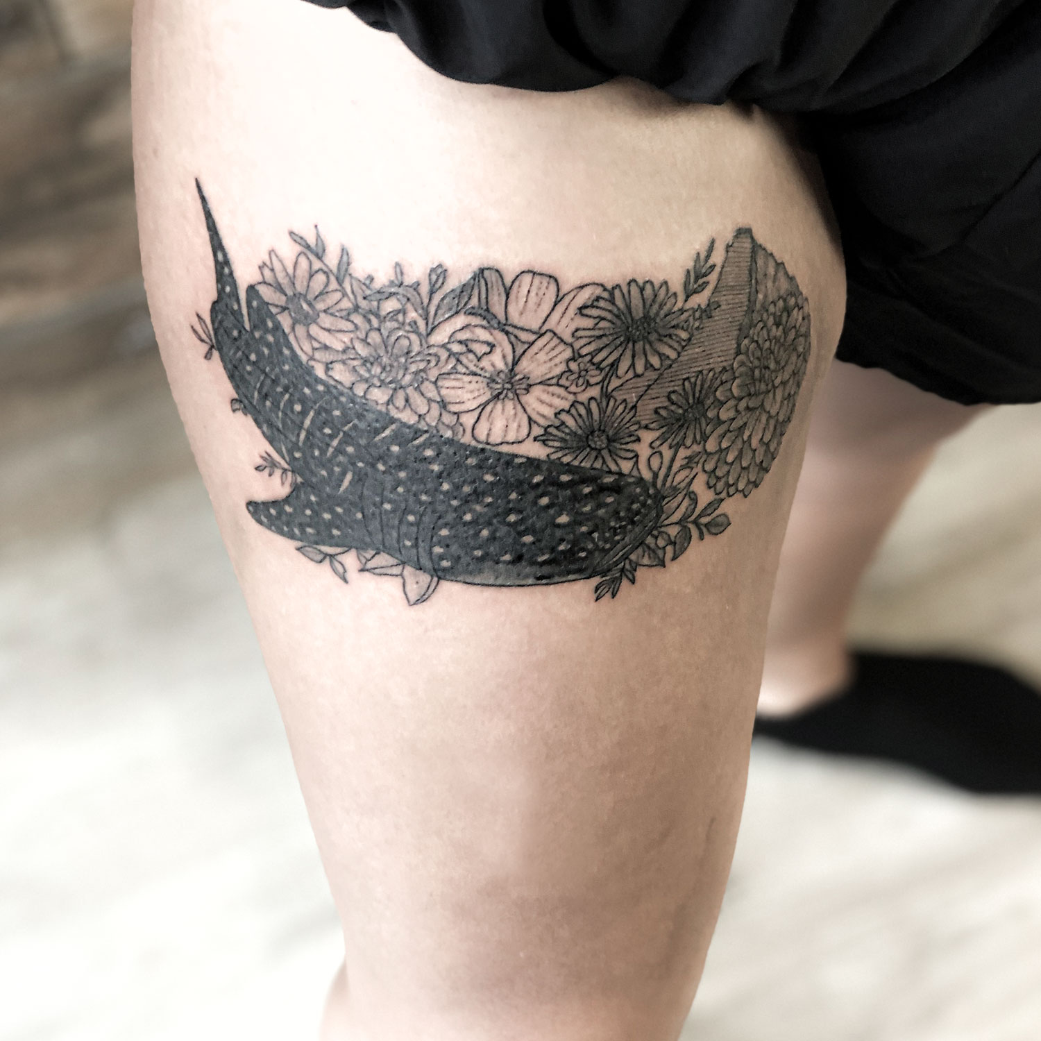 tatuaje blanco y negro de un tiburón ballena y unas flores