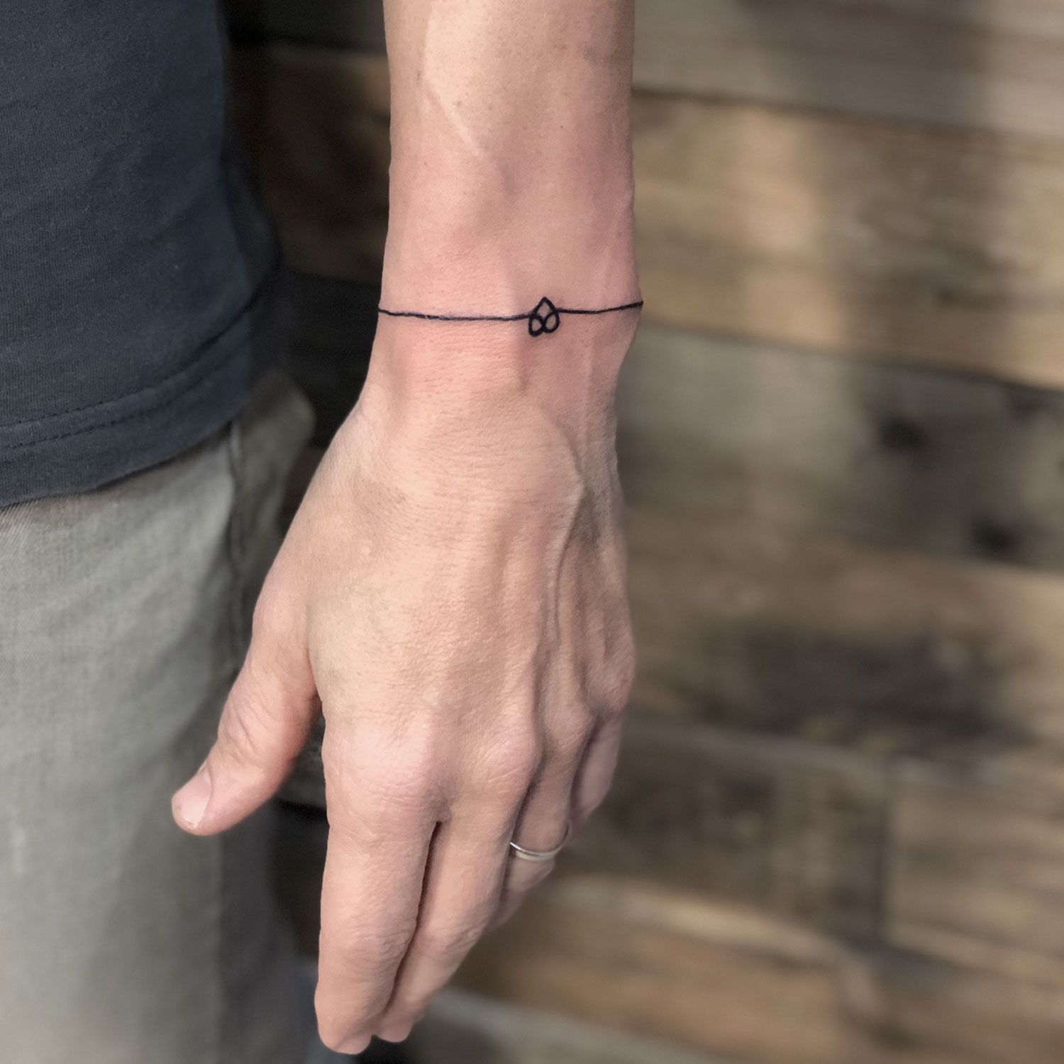 tatuaje blanco y negro de una pulsera con un corazón