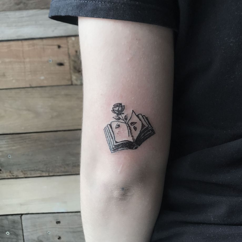 Tatuaje fine line de una rosa con un libro
