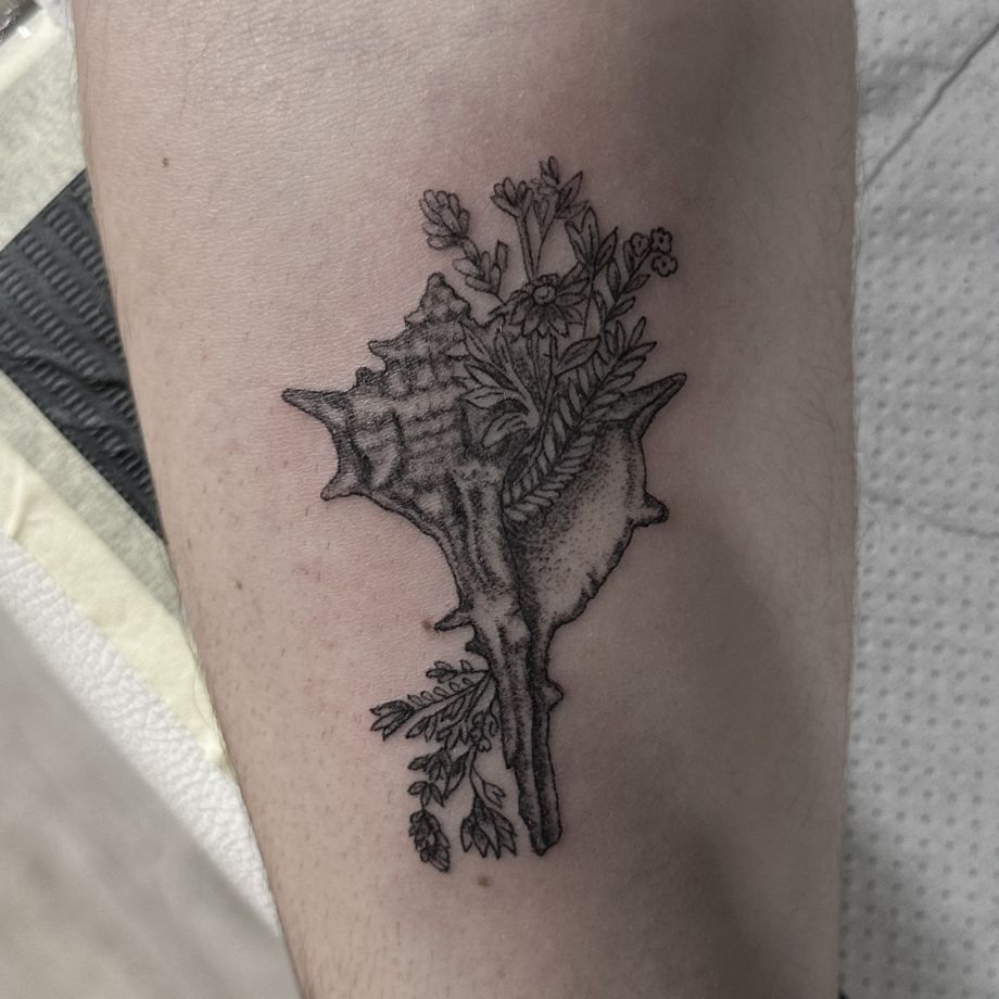Tatuaje black work de una caracola con flores