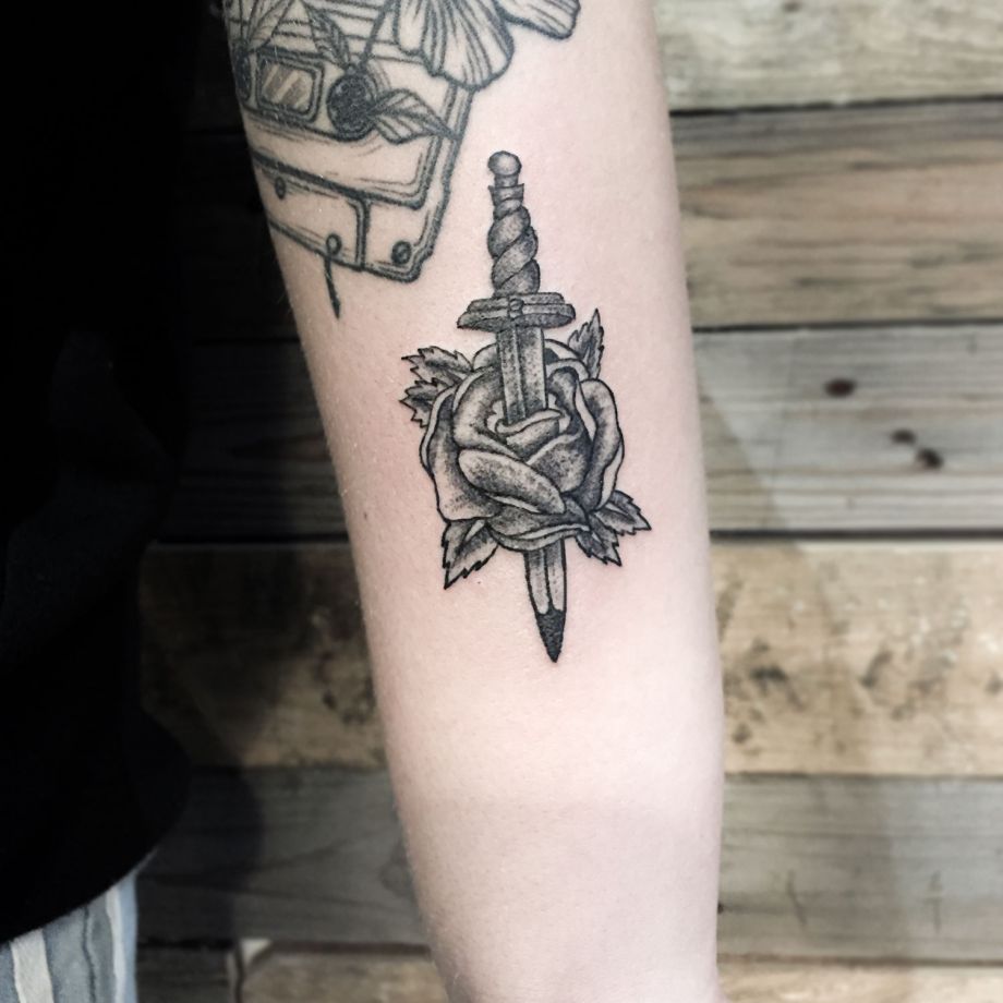 Tatuaje black work de una rosa atravesada por una daga